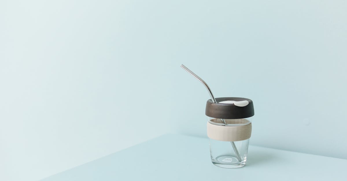 A stylish eco-friendly reusable cup with metal straw on a pastel background, promoting zero waste.